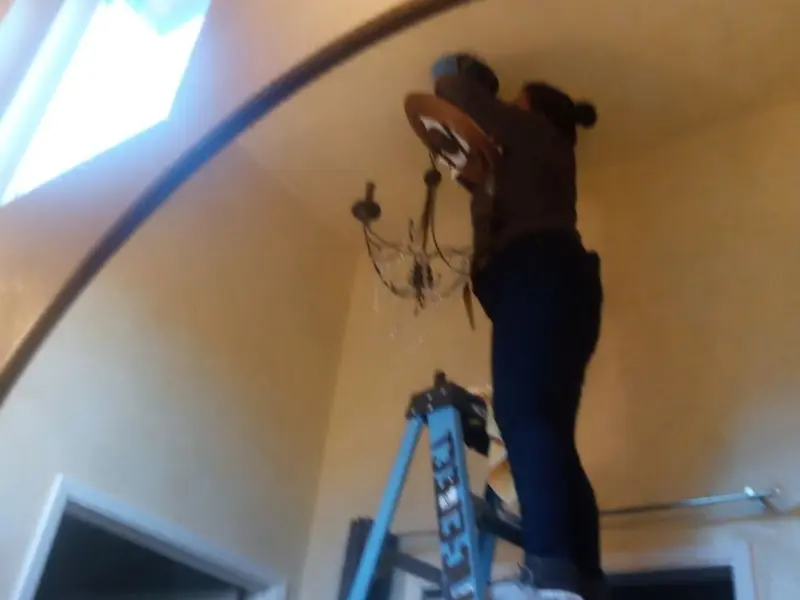 Electrician installing a chandelier in a Catalina residence